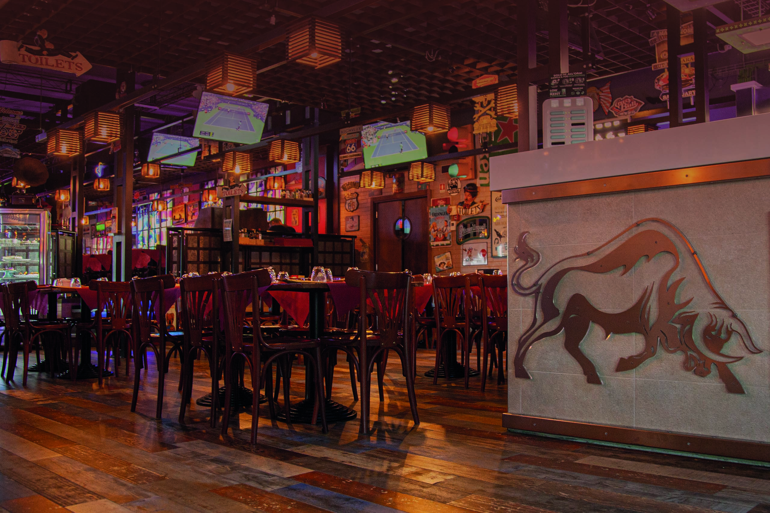 La sala del Crazy Bull di Surbo, con tavoli in legno, luci calde e arredi in stile pub americano
